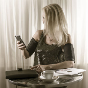 Attraktive Frau sitzt am Tisch und trägt SlimCOOL Power Arms